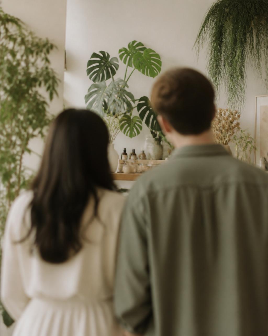 Two founders seen from behind in a plant-filled studio, softly out of focus